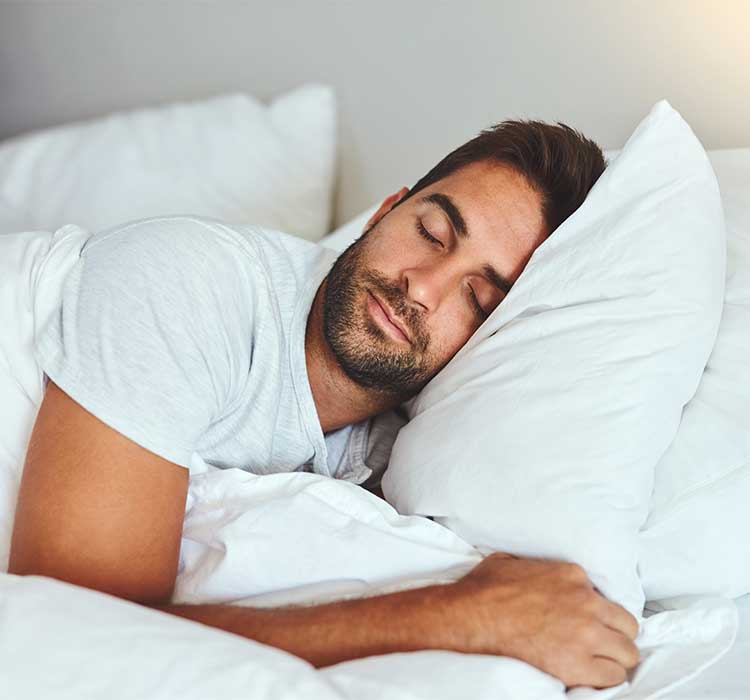 Man, sleeping and bed in morning rest for healthy wellness, peace and quiet on comfort pillow at home. Tired or exhausted male person asleep or dreaming on peaceful holiday or weekend in the bedroom