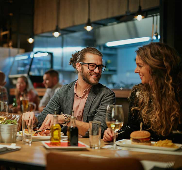 Group of friends sitting in retaurant and eating dinner.